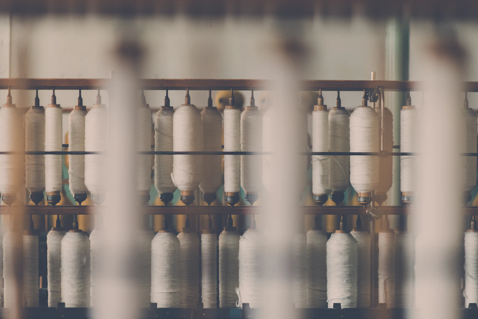 Cones of undyed cotton yarn stacked on a wooden rack