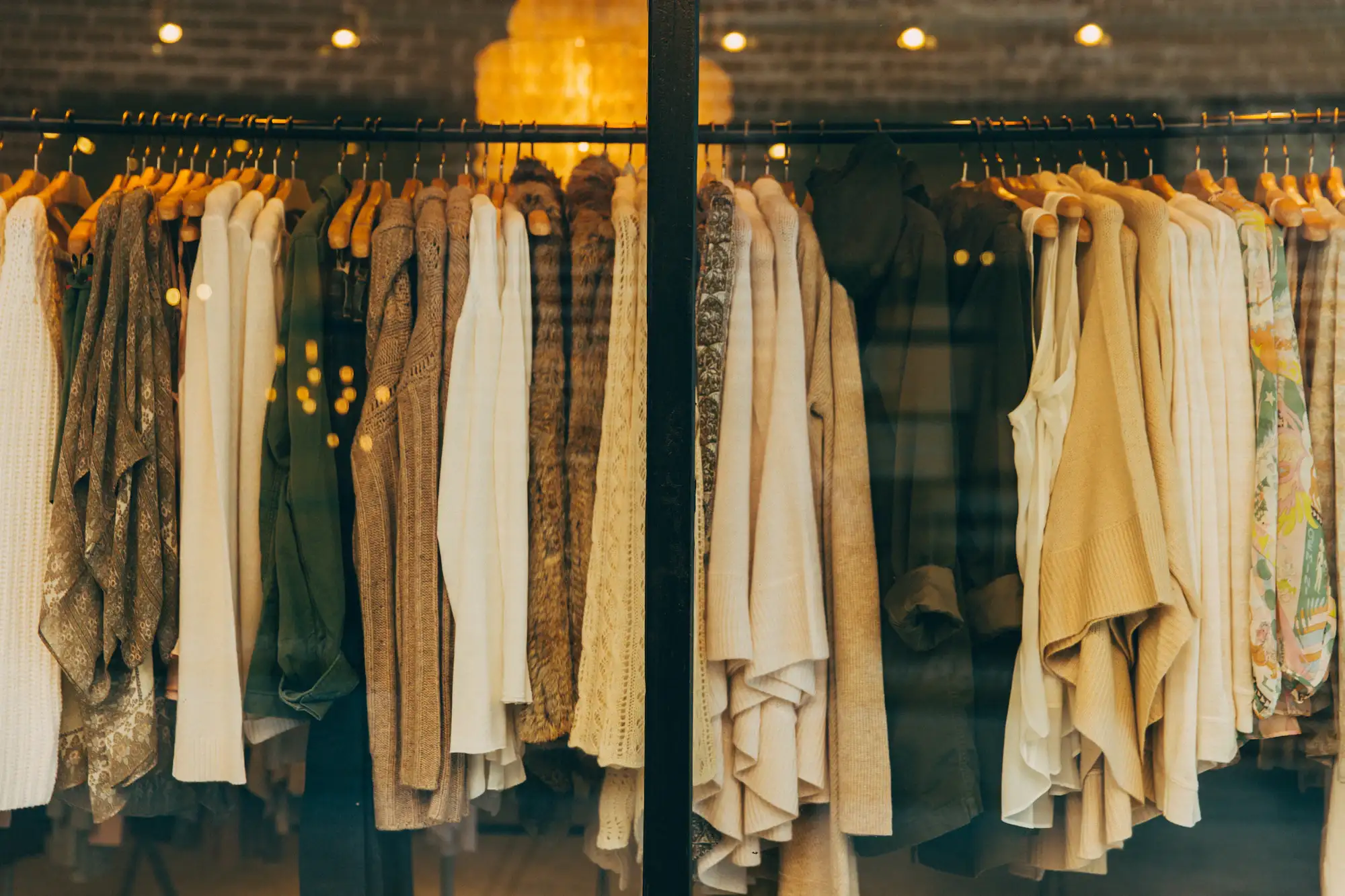 A daylit rail of ochre, cream and oat garments in natural fibres